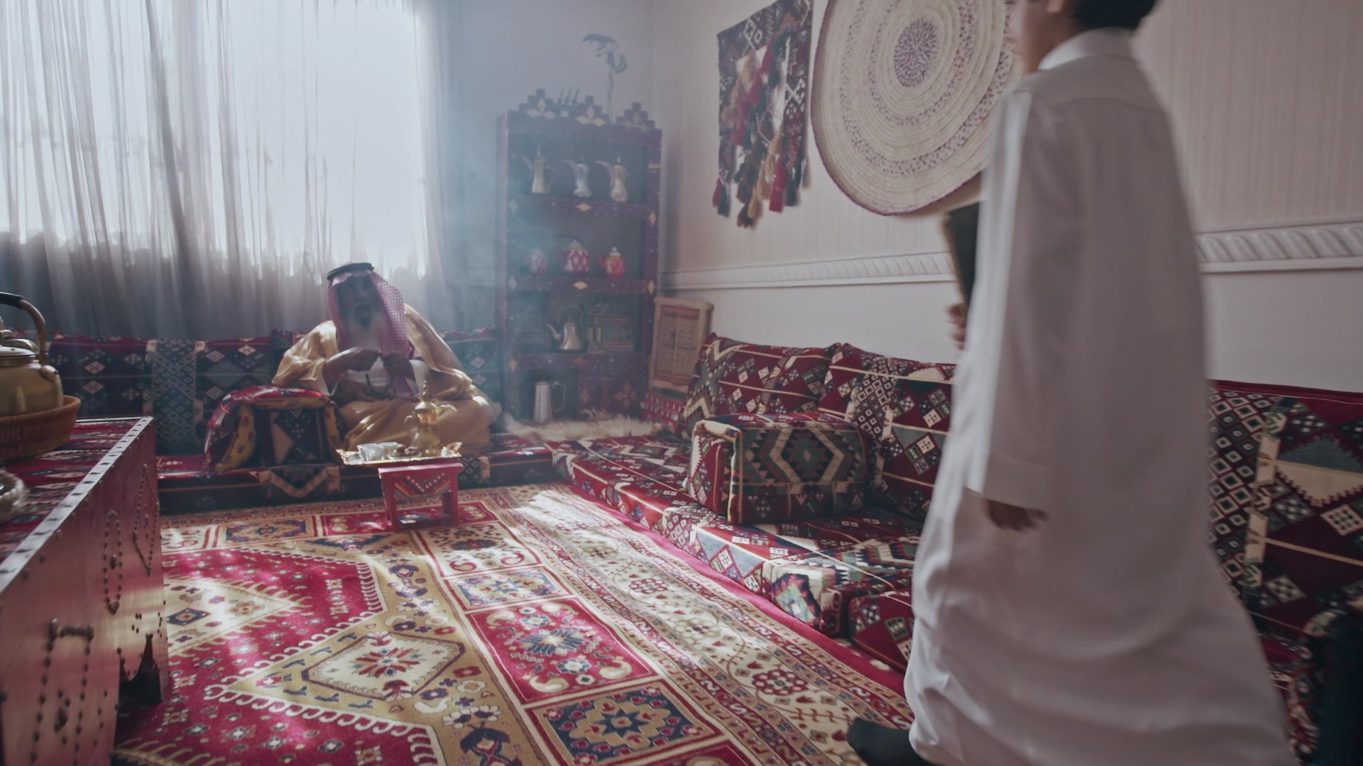 A boy walks into a majlis where his grandfather sits